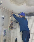 Bevor die Metallwerkstatt gestrichen wird, werden sämtliche Wände und Rohre von Anna abgeklebt. (Bild: THW/Nicola Kuhr)