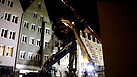 Der Bagger zieht an den Seilen und reißt das Giebelstück und einige Dachbalken kontrolliert in die Tiefe (Bild: Dieter Seebach/THW Augsburg)